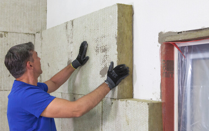 Die Mineralwolle-Dämmplatte wird an die Fassade geklebt.