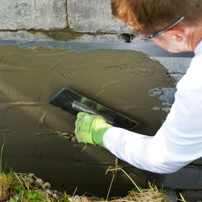 Fülle Unebenheiten an der Gartenmauer von mehr als 4 mm mit dem Baumit Gefälle- und Betonspachtel Fix aus, um eine ebene Fläche für die nachfolgende Dichtschlämme zu schaffen.